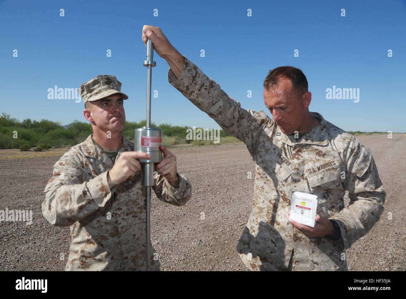 U.S. Marine Corps Chief Warrant Officer 3 Timothy Killebrew, a airfield emergency services officer assigned to Marine Wing Headquarter Squadron One, 1st Marine Aircraft Wing, and Capt. Shane Vickers, the commanding officer of Marine Wing Support Detachment 24, measures the soil subsurface with a dynamic cone penetrometer while attending the Weapons and Tactics Instructor (WTI) Course at Marine Corps Air Station Yuma, March 31, 2015. WTI is a seven week training event hosted by Marine Aviation Weapons and Tactics Squadron One (MAWTS-1) cadre. MAWTS-1 provides standardized tactical training and  Stock Photo