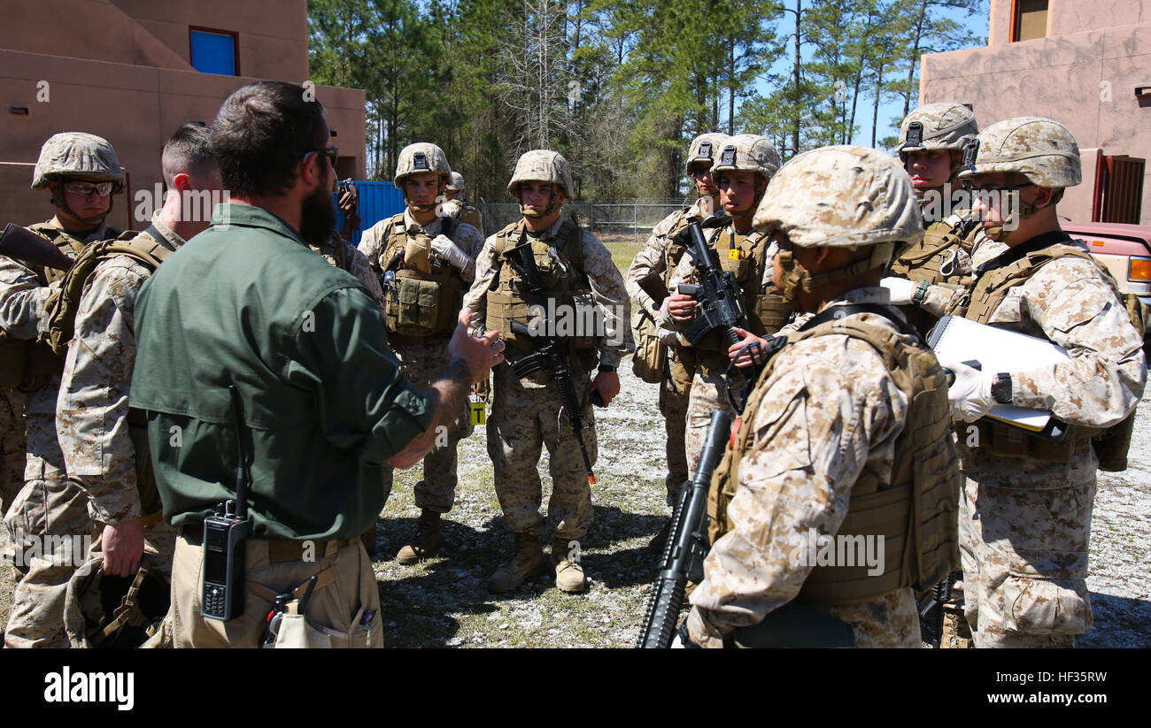 Zachary Rock, a counter-improvised explosive device instructor with A-T Solutions, a private training company with the Engineer Training School aboard Marine Corps Base Stone Bay, North Carolina, talks to Marines with Bravo Company, 1st Battalion, 8th Marine Regiment, after searching a compound during a Tactical Site Exploitation Course exercise at a Military Operations on Urban Terrain town aboard Camp Lejeune, North Carolina, April 2, 2015. with The training allowed Marines to gain experience on conducting a TSE and focused on teaching the Marines how to approach a building and thoroughly se Stock Photo