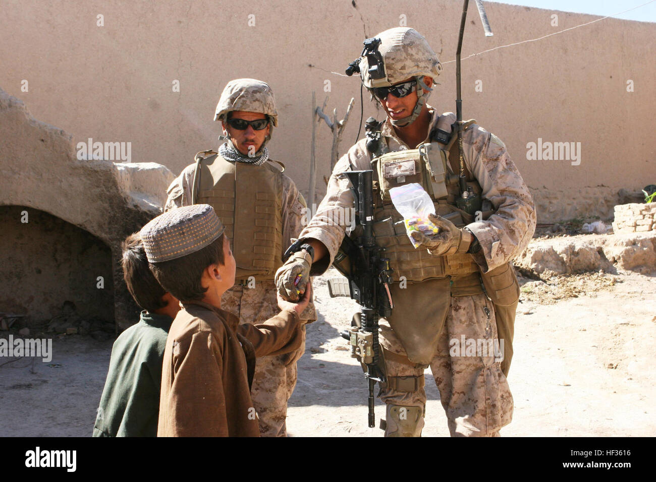 FORWARD OPERATING BASE INKERMAN, Helmand province, Islamic Republic of Afghanistan - Sgt. Juan A. Valdez, a squad leader for 81 mm Mortar Platoon, Weapons Company, 1st Battalion, 5th Marine Regiment, passes out Jolly Ranchers to Afghan children during Operation Kalawal Sunrise in the Village of Faiscal within Sangin, Afghanistan, June 1. “I had gone into one of the buildings before and the owner told me that he had been approached by fighters,” said Valdez, who planned the operation and led the Marines in its execution. “The local was told to move out of his compound because the enemy was goin Stock Photo