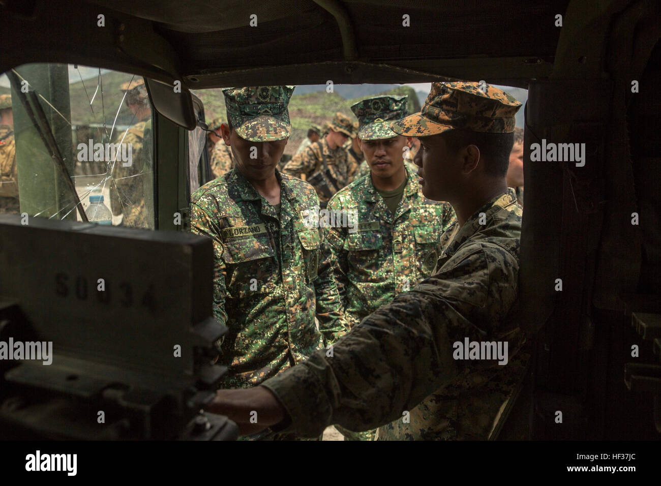 U.S. Marine Sgt. Darren Madrid, right, displays the interior of a Humvee to Philippine Marine Corps Pvts. Ariel Lorzano, left, and Almer Cuales, during a subject matter expert exchange class April 20 at Crow Valley, Philippines, in part of Exercise Balikatan 2015. The U.S. Marines and Filipino Marines were able to learn each other’s standard operating procedures for corrective maintenance on logistical vehicles. Exercise Balikatan is a bilateral training exercise between the Armed Forces of the Philippines and U.S. military to increase Madrid is a motor transportation operator currently assign Stock Photo