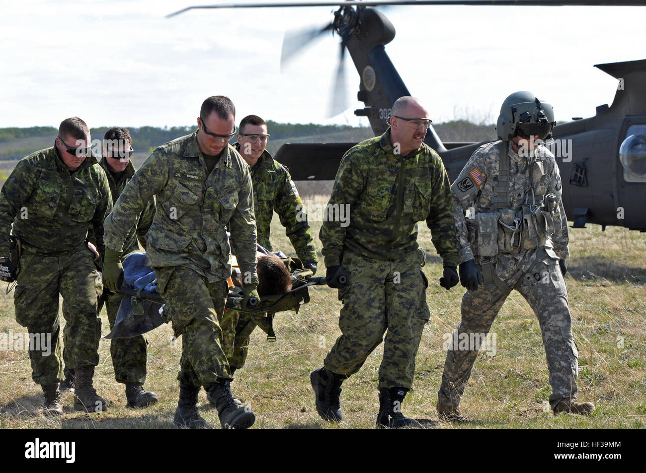 Oregon Army National Guard Sgt. Michael Buchan, a flight medic with Charlie Company, 7-158 Aviation, escorts members of the Canadian Armed Forces transporting a patient away from an HH-60M Black Hawk helicopter during Exercise Maple Resolve at Canadian Forces Base Wainright, May 7, in Denwood, Alberta. The Oregon Army National Guard medevac unit is providing support during the Canadian Armed Forces' largest annual exercise. Oregon Army National Guard flight medics lead the way 150507-Z-AH721-282 Stock Photo