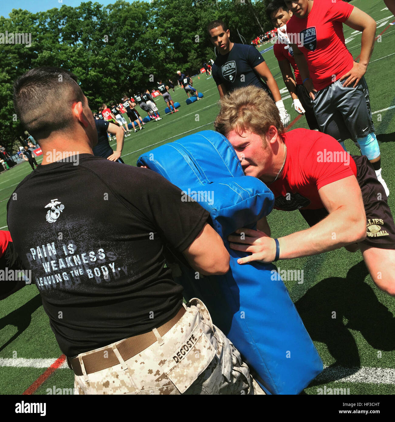 Sergeant Paul Decoste holds a body pad as high school football players rehearse offensive drills during the Semper Fidelis All-American Camp at St. John Preparatory High School in Danvers, Massachusetts, June 7. Nearly 200 top football players from high schools throughout the New England states, including New York, Pennsylvania and New Jersey, received training from the NFL and college football coaches while fighting for a spot to play in the 2016 Semper Fidelis All-American Bowl game in California. Decoste is a canvassing recruiter for Recruiting Substation Lawrence, Mass., Recruiting Station Stock Photo
