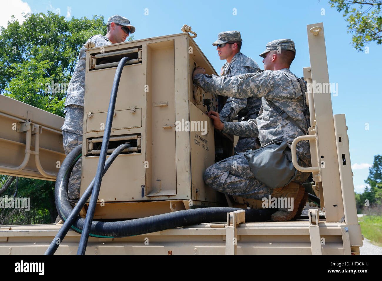 Spc. Dominic Ashley, Spc. Casey Shockey, and Pfc. Austin Eldridge, assigned to the 3175th Chemical Company, 835th Combat Sustainment Support Brigade, work together to set up an M12A1 Power Driven Decontamination Apparatus in preparation for a decontamination exercise during annual training on June 8, 2015 at Fort Leonard Wood, Mo. Soldiers manned five stations, three equipped with PDDAs, to clean and decontaminate vehicles after a simulated chemical attack. (U.S. Army photo by Pfc. Samantha J. Whitehead) Missouri Guard Chemical Company trains to keep troops, equipment safe 150608-Z-YF431-016 Stock Photo