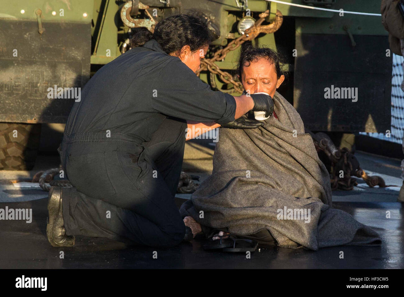 A U.S. Navy Sailor provides water to a distressed mariner aboard the