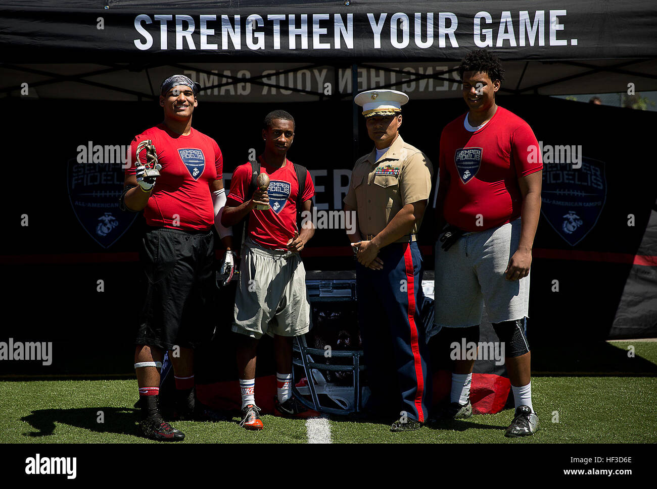 Maj. Sung Kim, the commanding officer of Marine Corps Recruiting Station Seattle, presents awards to Avyion Fisher (left) from Bethel High School; Emmanuel Wells (center) from Rainier Beach High School; and Taven Erpenbach (right) from Gig Harbor High School following a Semper Fidelis All-American football camp at Hazen High School in Renton, Washington, June 14, 2015. More than 160 players from across Washington State experienced the one-day camp, led by former NFL coaches, local high school coaches and Marines. The camp, which focused on leadership and honor both on and off the field, leads  Stock Photo