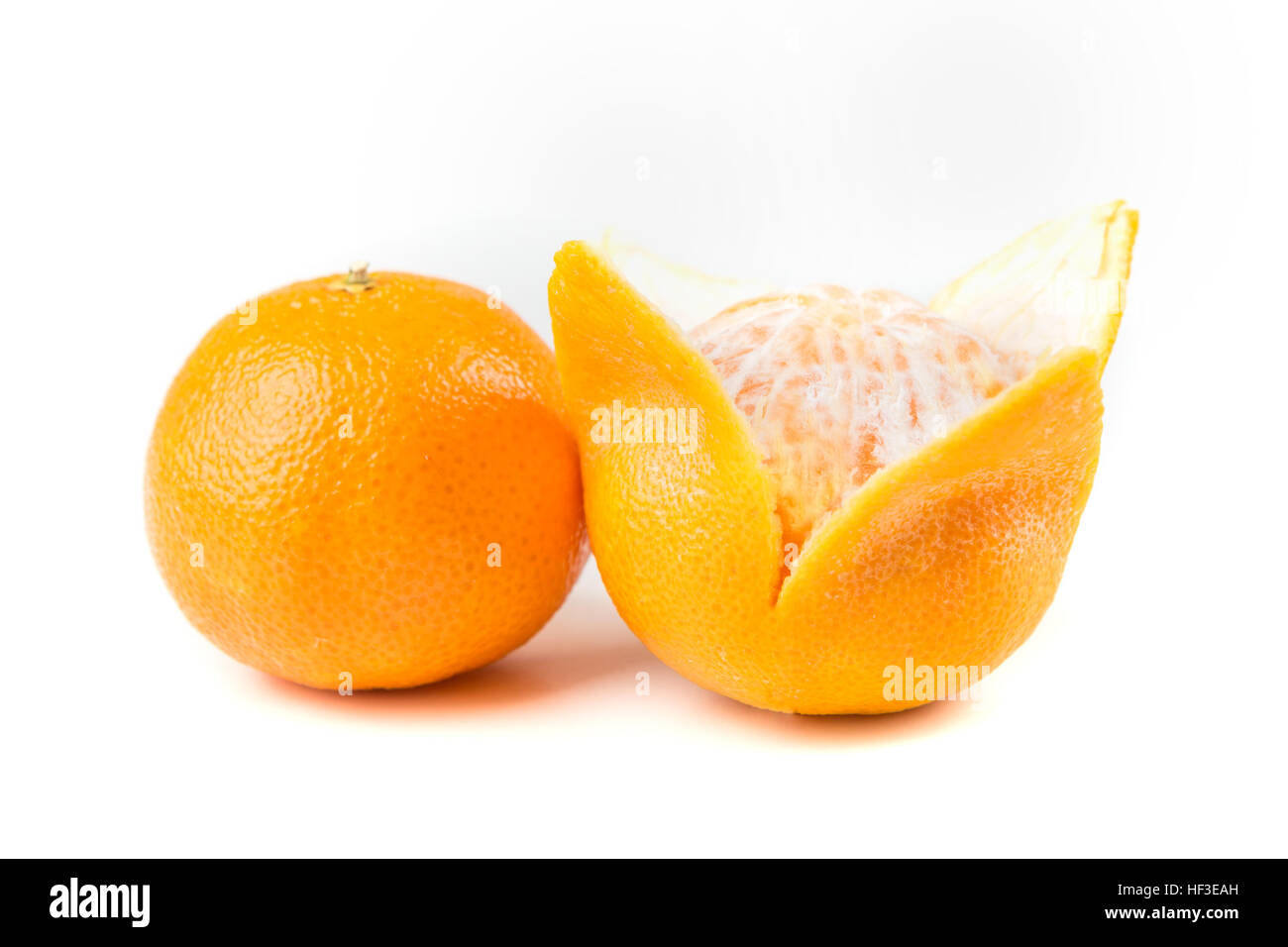 Two navel oranges one peeled one unpeeled isolated on white background