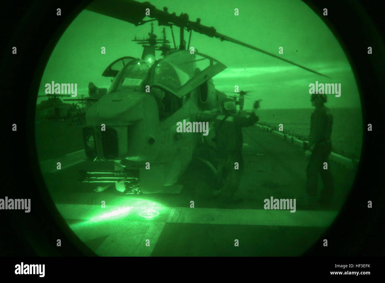 U.S. Marine Lance Cpl. James R. Shugart (left) and Cpl. Kyle C. Lyons (right), helicopter mechanics with the night crew, Marine Medium Tiltrotor Squadron (VMM) 162 (REINFORCED), 26th Marine Expeditionary Unit (MEU), signal to the pilot and co-pilot of an AH-1 Super Cobra to start the engines for a pre-flight maintenance check prior to take-off during an Amphibious Ready Group/Marine Expeditionary Unit Exercise (ARG/MEU-Ex) aboard the USS Kearsarge, June 25, 2015. The 26th MEU and Amphibious Squadron 4 are conducting an ARG/MEU-Ex in preparation for their deployment to the 5th and 6th Fleet are Stock Photo