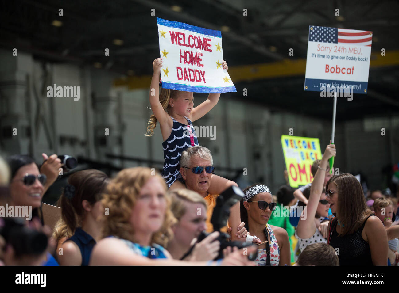 A daughter of a Marine assigned to Marine Medium Tiltrotor Squadron 365 (Reinforced), 24th Marine Expeditionary Unit, displays a “welcome home” sign for the VMM 365 (Rein) homecoming at Marine Corps Air Station New River, N.C., July 16, 2015. Marines and Sailors of the 24th MEU were embarked on the ships of the Iwo Jima Amphibious Ready Group and supported operations in the U.S. 5th and 6th Fleet area of operations. They also took part in numerous theater security cooperation exercises and training with allied partners such as Djibouti, Italy, Oman, Spain, France, Jordan, Israel, United Arab E Stock Photo