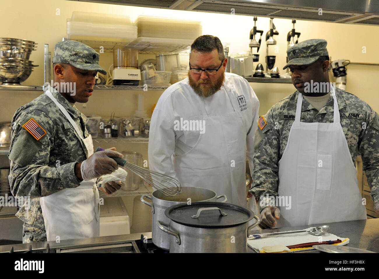 Spc. Kevius Willis, of Edwards, Miss., assigned to Headquarters Company, 106th Support Battalion, 155th Armored Brigade Combat Team, Chef Chris Ellis, and Spc. Jermaine Burns, of Indianola, Miss., assigned to the 1387th Quartermaster Company, Mississippi Army National Guard (MSARNG) discuss spicy brown rice pilaf during a food service workshop conducted by the Culinary Arts Institute at the Mississippi University for Women on July 23, 2015.  The eighth-annual workshop provided MSARNG food service specialists with lecture and hands-on skill development designed not only to focus on the basics,  Stock Photo