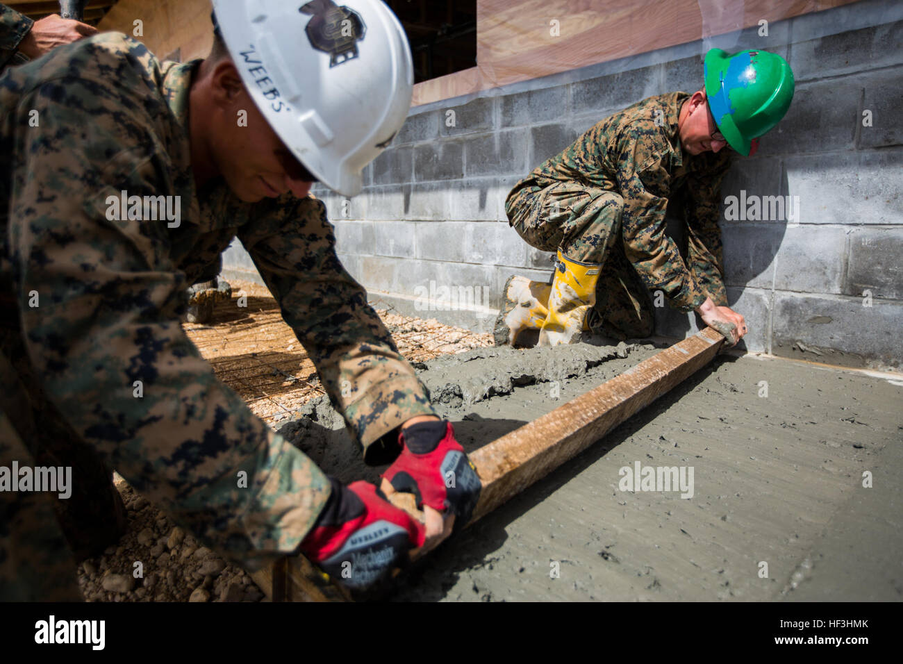 U.S. Marine Corps Lance Cpl. Ethan Shireman, right, a combat engineer with Special Purpose Marine Air-Ground Task Force-Southern Command and Lance Cpl. Silas Weibel, a combat engineer with SPMAGTF-SC smooth wet concrete while assisting with Jardin de Niños: El Porvenir, a reconstructed school, in Puerto Lempira, Honduras, July 29, 2015. SPMAGTF-SC is a temporary deployment of Marines and Sailors throughout Honduras, El Salvador, Guatemala, and Belize with a focus on building and maintaining partnership capacity with each country through shared values, challenges, and responsibility. (U.S. Mari Stock Photo