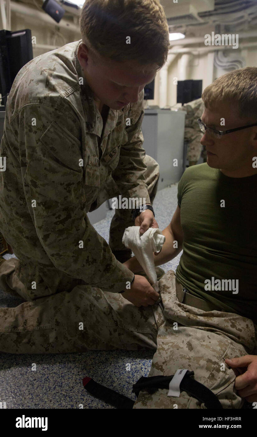 Lance Cpl. Nathan Lynch, a heavy equipment operator, with the Engineer Detachment, Combat Logistics Battalion 26, 26th Marine Expeditionary Unit (MEU), applies combat gauze to stop a simulated massive bleeding injury in the junction area on a simulated casualty during a Combat Life Saver Course aboard the USS Arlington (LPD 24) Aug. 1, 2015. Marines with the 26th MEU and sailors with the Kearsarge Amphibious Ready Group are participating in the Composite Training Unit Exercise (COMPTUEX) in preparation for their upcoming deployment to the 5th and 6th Fleet areas of responsibility later this fa Stock Photo