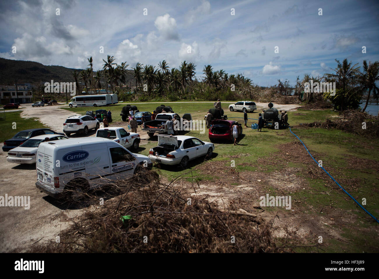 Vehicles wait in line as U.S. Marines with Combat Logistics Battalion 31, 31st Marine Expeditionary Unit, distribute water to local civilians during typhoon relief efforts in Saipan, Aug. 12, 2015. The 31st MEU and the ships of the Bonhomme Richard Amphibious Ready Group are assisting local and federal agencies with distributing emergency relief supplies to Saipan after the island was struck by Typhoon Soudelor Aug. 2-3. (U.S. Marine Corps photo by Gunnery Sgt. Ismael Pena/Released) Marines bring clean water to people of Saipan 150812-M-MX588-163 Stock Photo