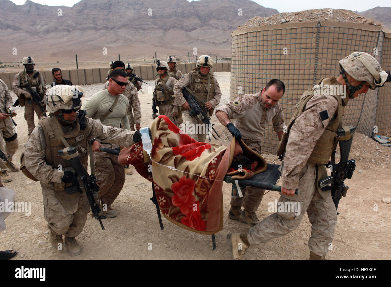 Marines and Sailors assigned to India Company, 3rd Battalion, 4th Marine Regiment tend to the medical needs of an injured boy near Forward Operating Base Golestan in Helmand province, Afghanistan. The boy fell from an unknown height and was in critical condition. Caring for an injured child DVIDS220033 Stock Photo