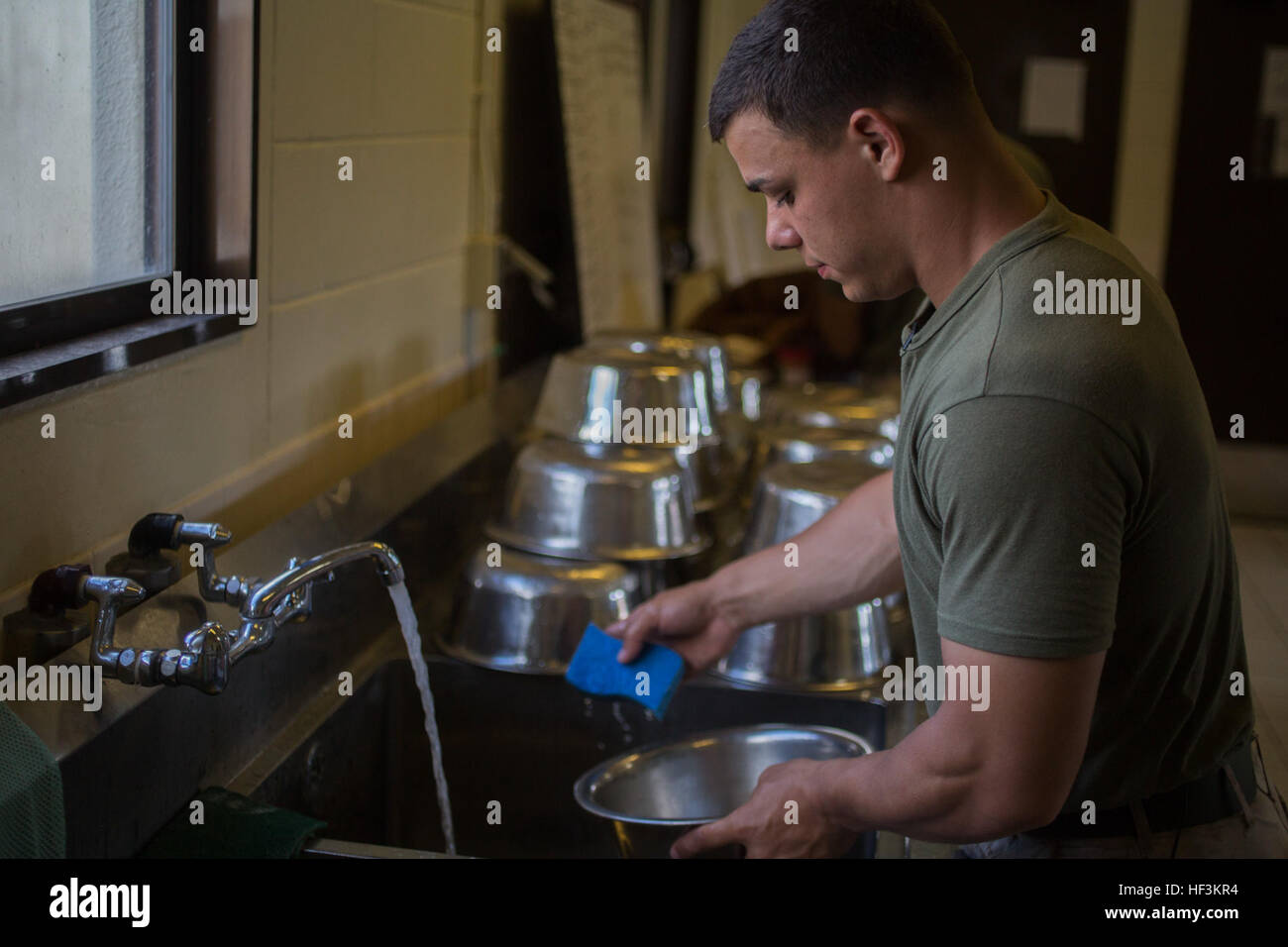 Lance Cpl. Donald Hesse cleans out the dogs' food bowls after feeding them for the last time before they depart Kadena Air Base, Okinawa, Japan, Sept. 24, 2015. Being a dog handler is an all day, every day job; they work from the time they get to the kennels early in the morning until the last time they feed them for the day. Hesse is a military working dog handler with 3rd Law Enforcement Battalion, III Marine Expeditionary Force Headquarters Group, III MEF. Dasty is a Belgian Malinois and a patrol explosive detection dog. (U.S. Marine Corps Photo by Cpl. Thor J. Larson/Released) Every Dog ha Stock Photo