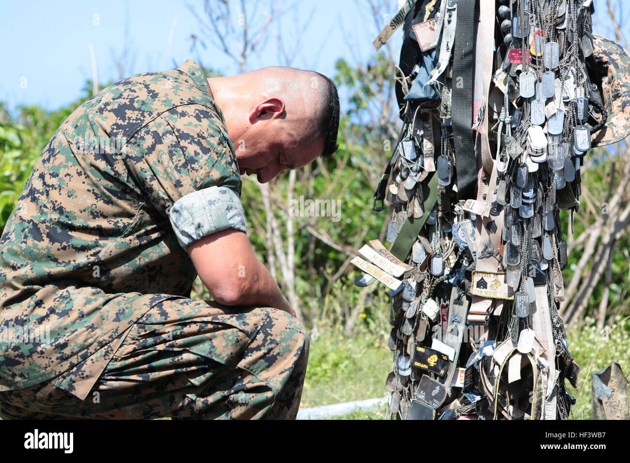 U.S. Marine Corps Sergeant Major Mario A. Marquez , sergeant major,  1st Marine Aircraft Wing, kneels at a memorial to pay his respects atop Mount Suribachi at Iwo To, Japan, March 19, 2015. The Iwo Jima Reunion of Honor is an opportunity for Japanese and U.S. veterans and their families, dignitaries, leaders and service members from both nations to honor the battle while recognizing 71 years of peace and prosperity in the U.S. – Japanese alliance. (U.S. Marine Corps photo by MCIPAC Combat Camera Lance Cpl. Juan Esqueda / Released) Iwo Jima 71st Reunion of Honor 160319-M-JD520-046 Stock Photo
