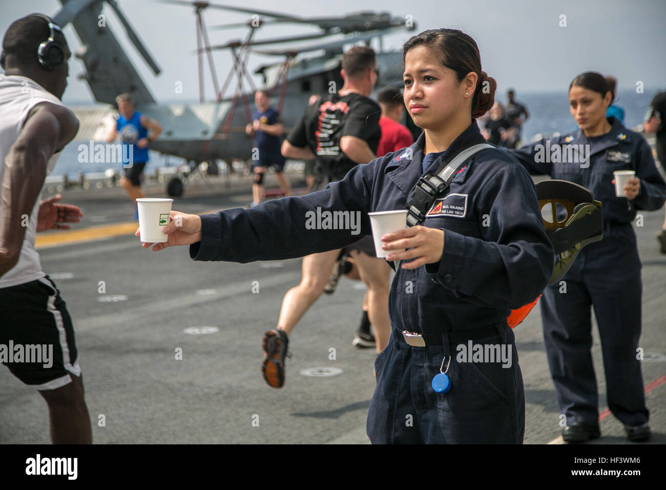 At sea. (March 27, 2016)-U.S. Sailor HM2 Charissa Caayao, with the 13th Marine Expeditionary Unit and Boxer Amphibious Ready Group team, hands out water to participants in a 5k run for women's history month, March 27, 2016, during the MEU's western pacific deployment aboard the USS Boxer. More then 4,500 Marines and Sailors from the Boxer ARG, 13th MEU team are currently transiting the Pacific Ocean toward the U.S. 5th fleet area of operations during a scheduled deployment. (U.S. Marine Corps photo by Sgt. Briauna Birl/RELEASED) Women's History 5k aboard USS Boxer 160327-M-KR317-130 Stock Photo