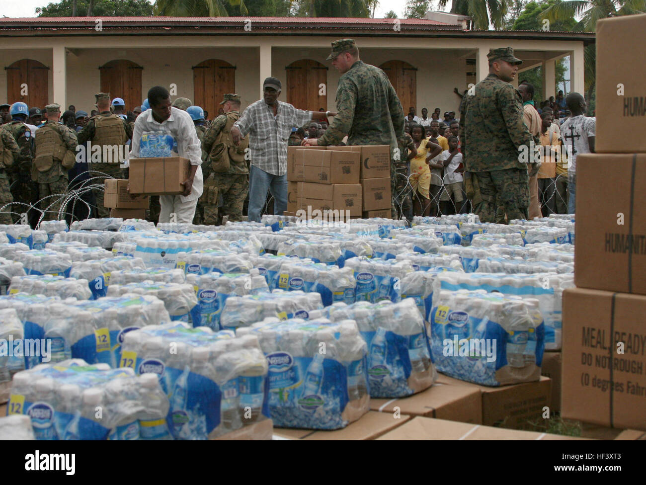 A Haitian man receives rations and water at a distribution site set up ...