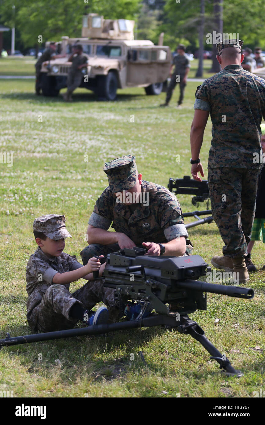 Gunnery Sgt. Joseph Ascone, an electronics maintenance technician with Combat Logistics Regiment 2, describes the components of a Mk 19 Grenade Launcher as a young boy sits behind the weapon system during the unit’s Bring Your Sons and Daughters to Work Day at Camp Lejeune, N.C., April 28, 2016. The unit set up several displays for the kids to check out it gave them insightabout what their parents do  in the Marine Corps. (U.S. Marine Corps photo by Cpl. Dalton A. Precht/released) Family matters, Marines, families of CLR-2 enjoy static displays and games 160428-M-WI309-044 Stock Photo