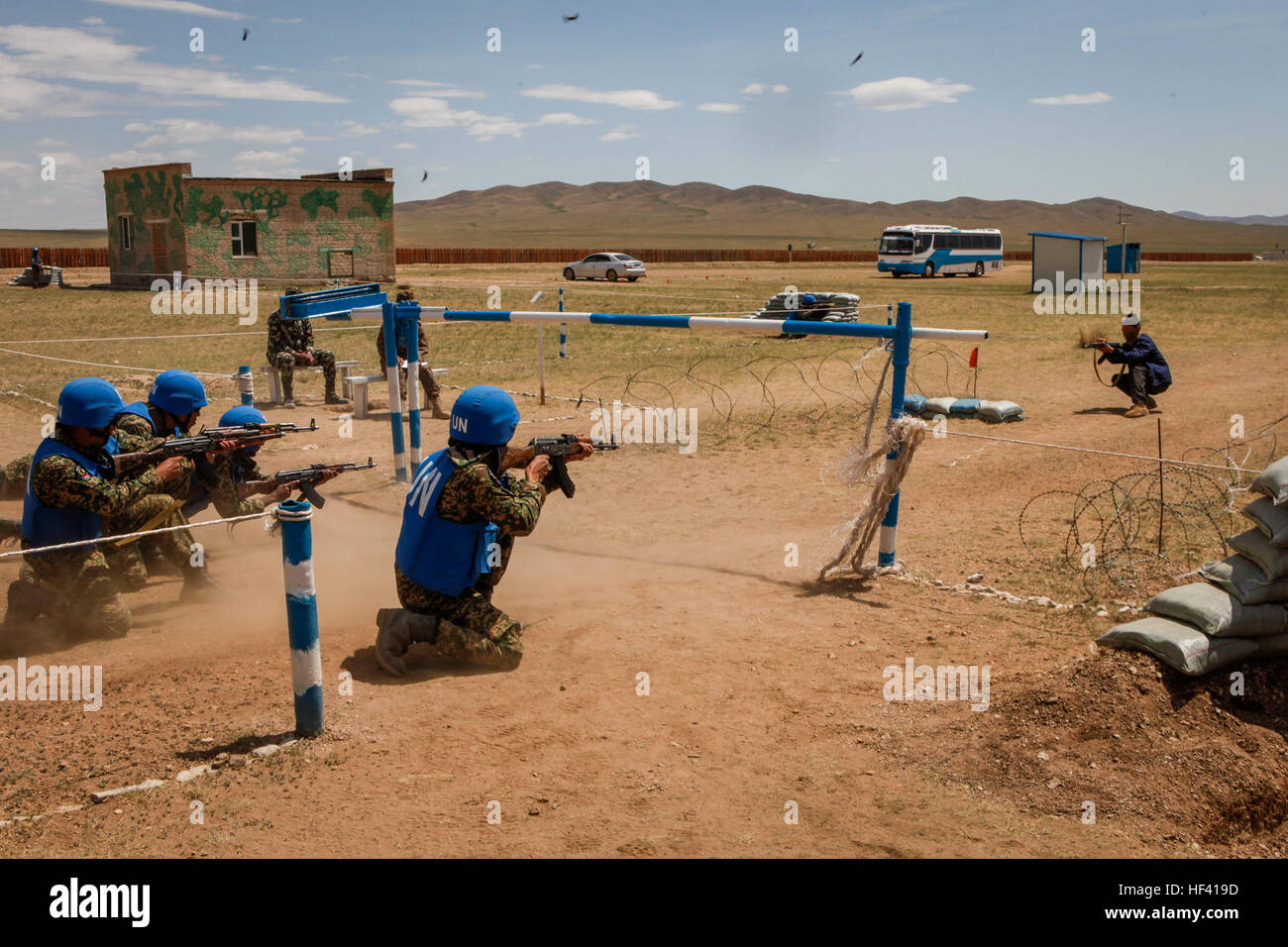 Service members with the Malaysian Army post security while being engaged by simulated fire during the riot control training lane at Khaan Quest 2016, Five Hills Training Area, Mongolia, June 1, 2016. The riot control training is one of eleven training lanes set up at Khaan Quest for the multinational platoons that equip participants with the skills necessary to face any situation that may arise during peacekeeping operations. Khaan Quest is an annual, multinational peacekeeping operations exercise hosted by the Mongolian Armed Forces, co-sponsored by U.S. Pacific Command, and supported by U.S Stock Photo