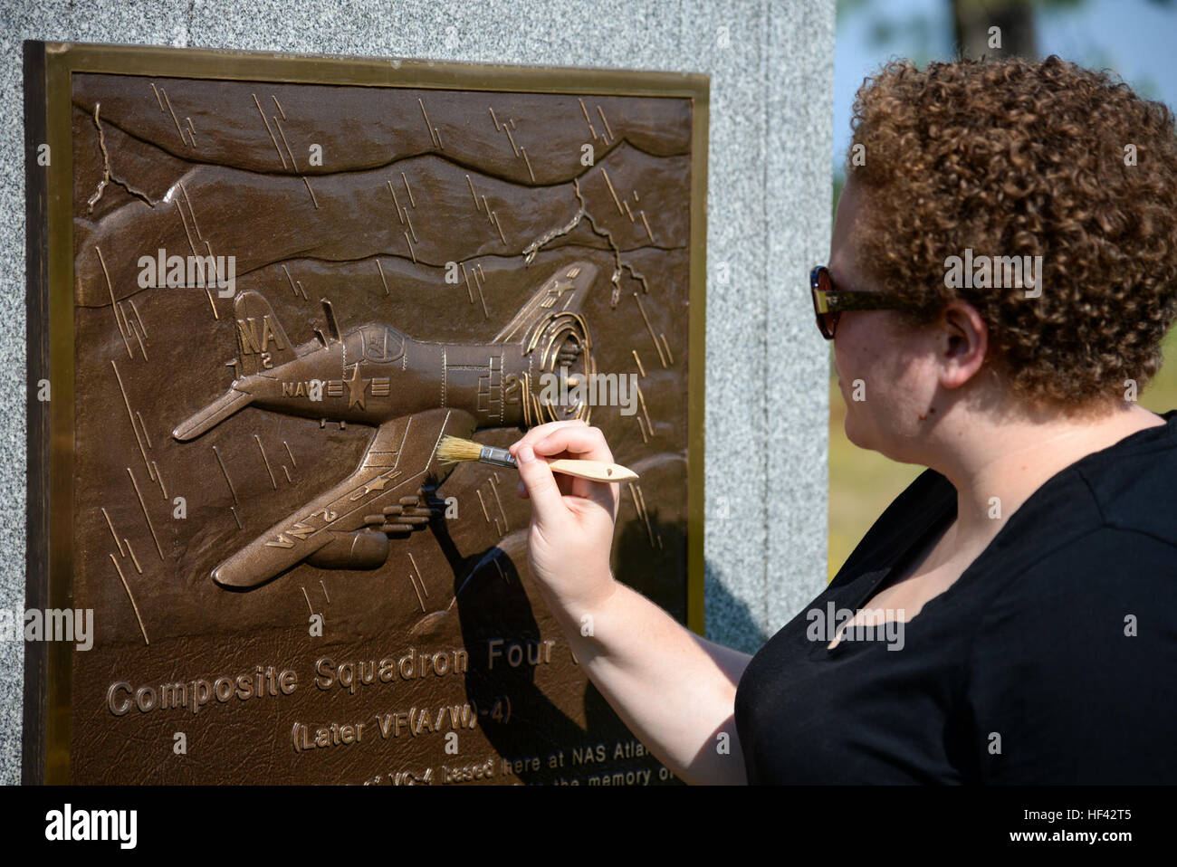 Melissa Swanson, Naval History and Heritage Command Conservator, applies a protective wax polish to a U.S. Navy VC-4 memorial marker, located near the main gate of the 177th Fighter Wing of the New Jersey Air National Guard in Egg Harbor Township, N.J., on July 21, 2016. The monument, erected in May 1994 by the Association of The Composite Squadron Four Nightcappers, pays tribute to the members of the VC-4 Squadron based at Naval Air Station Atlantic City from September 1948 to May 1958 who gave the ultimate sacrifice. Swanson, based out of Richmond, Virginia, earned an undergraduate degree in Stock Photo