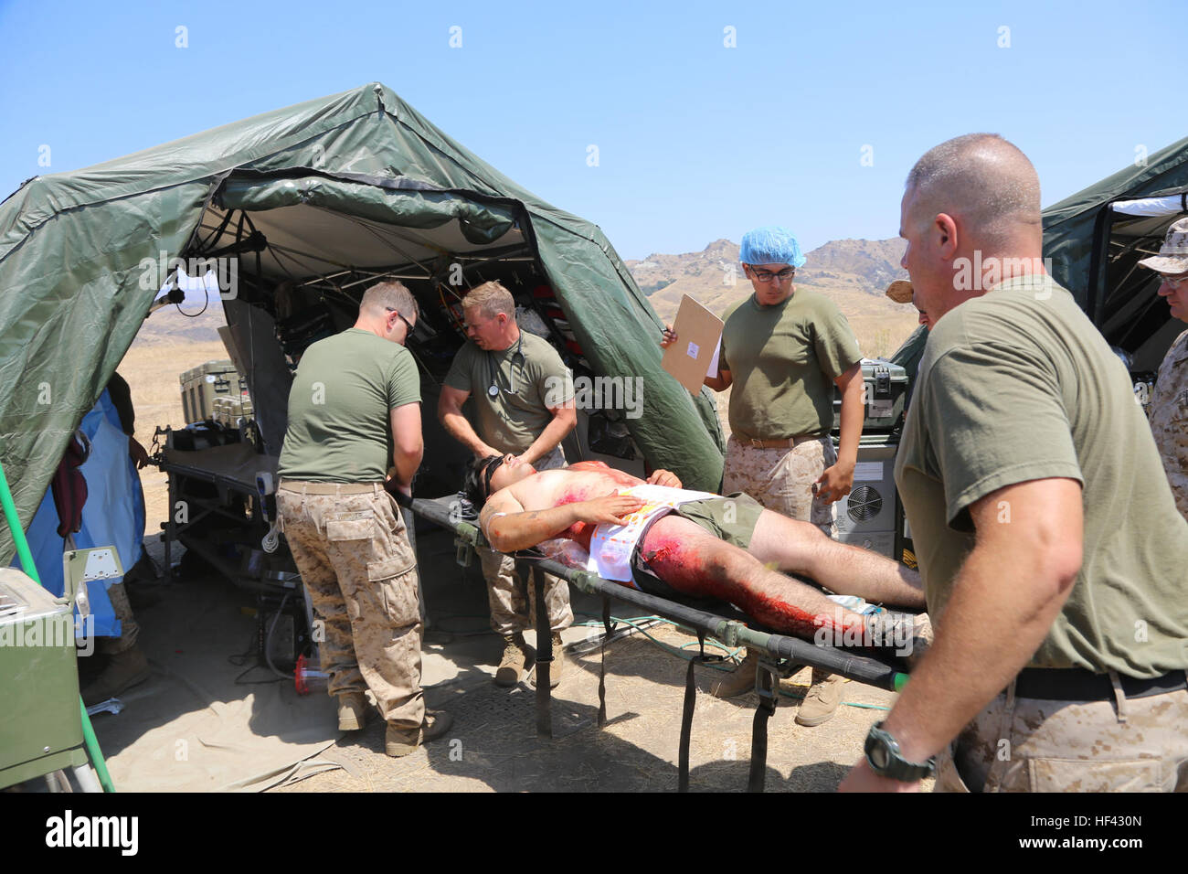 MARINE CORPS BASE CAMP PENDLETON, California (July 29, 2016)  – U.S. Navy corpsmen from 1st  Medical Battalion transport a victim of simulated combat-related trauma into the operating tent aboard Camp Pendleton, July 29, 2016. Navy surgeons, doctors and nurses participate in the exercise during the Marine Corps Warfighting Lab Marine Air-Ground Task Force Integrated Experiment that will test the capabilities of new deployable medical equipment and the efficiency of using the least amount of supplies and personnel to achieve the most mobile and optimal care for damage control and resuscitative  Stock Photo