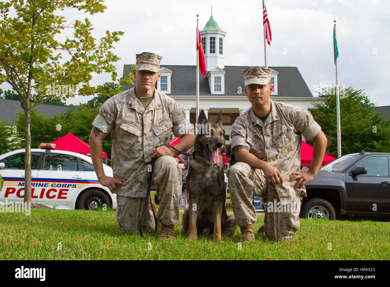 Sergeant Shawn R. Edens (right) and Cpl. Braxton H. Rico (left) pose for a picture with Segal (middle) before the 2016 National Night Out begins outside of Lincoln Military Housing aboard Marine Corps Base Quantico, Va., Aug. 2. The purpose of the event is to strengthen relationships between police forces and community partnerships while increasing public awareness of Quantico’s Security Battalion. Edens and Rico are assigned to Security Battalion aboard MCB Quantico. Segal is a German shepherd who was Edens’ last dog to handle, but is now Rico’s first. Pack Leader, Marine Military Working Dog Stock Photo