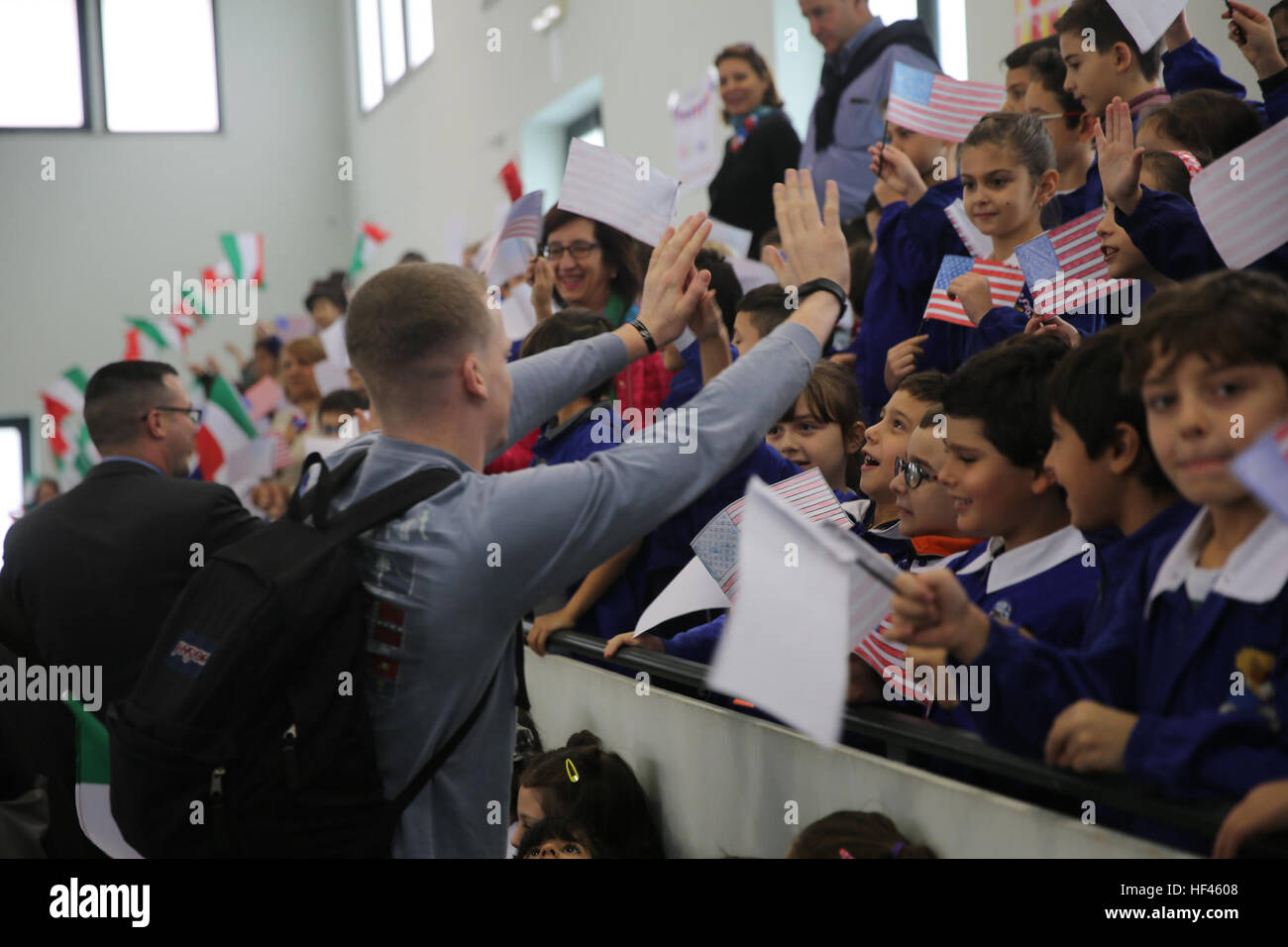 Lance Cpl. Conor Fredericks, an intelligence analyst with Special Purpose Marine Air-Ground Task Force Crisis Response-Africa, gives Italian elementary students hi-fives during a community relations event at San Giovanni Bosco Elementary School in Giarre, Italy, November 15, 2016. The Marines and sailors of SPMAGTF-CR-AF spent time with the children teaching classes on nutrition, exercising and taking many group photos to promoting a positive relationship between the United States and Italy. (U.S. Marine Corps photo by 1st Lt. Eric Abrams/released) Marines and sailors make connection with Ital Stock Photo
