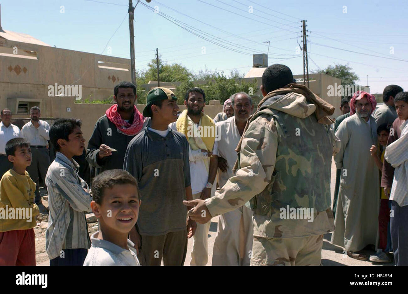 030402-M-0000X-001 Nasiryah, Iraq (Apr. 2, 2003) -- Mousa al Mousa, an interpreter with the Free Iraq Forces (FIF) meets and speaks with residents of an outlying town on the outskirts of Nasiriyah.  Mousa is assigned to the 4th Civil Affairs Group to drop off medical supplies to a clinic being used to treat local residents.  FIF personnel are Shiia and Sunni Muslims, Arabs and Kurds, all exiled from Iraq, who are committed to democracy and securing peace in their homeland.  The soldiers wear battle-dress uniforms with “FIF” patches on the shoulder and assist U.S. and coalition forces in civil- Stock Photo