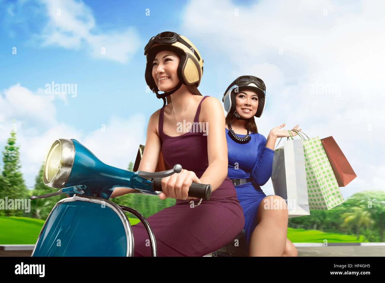 Attractive two asian girl riding a scooter on a daylight in the city