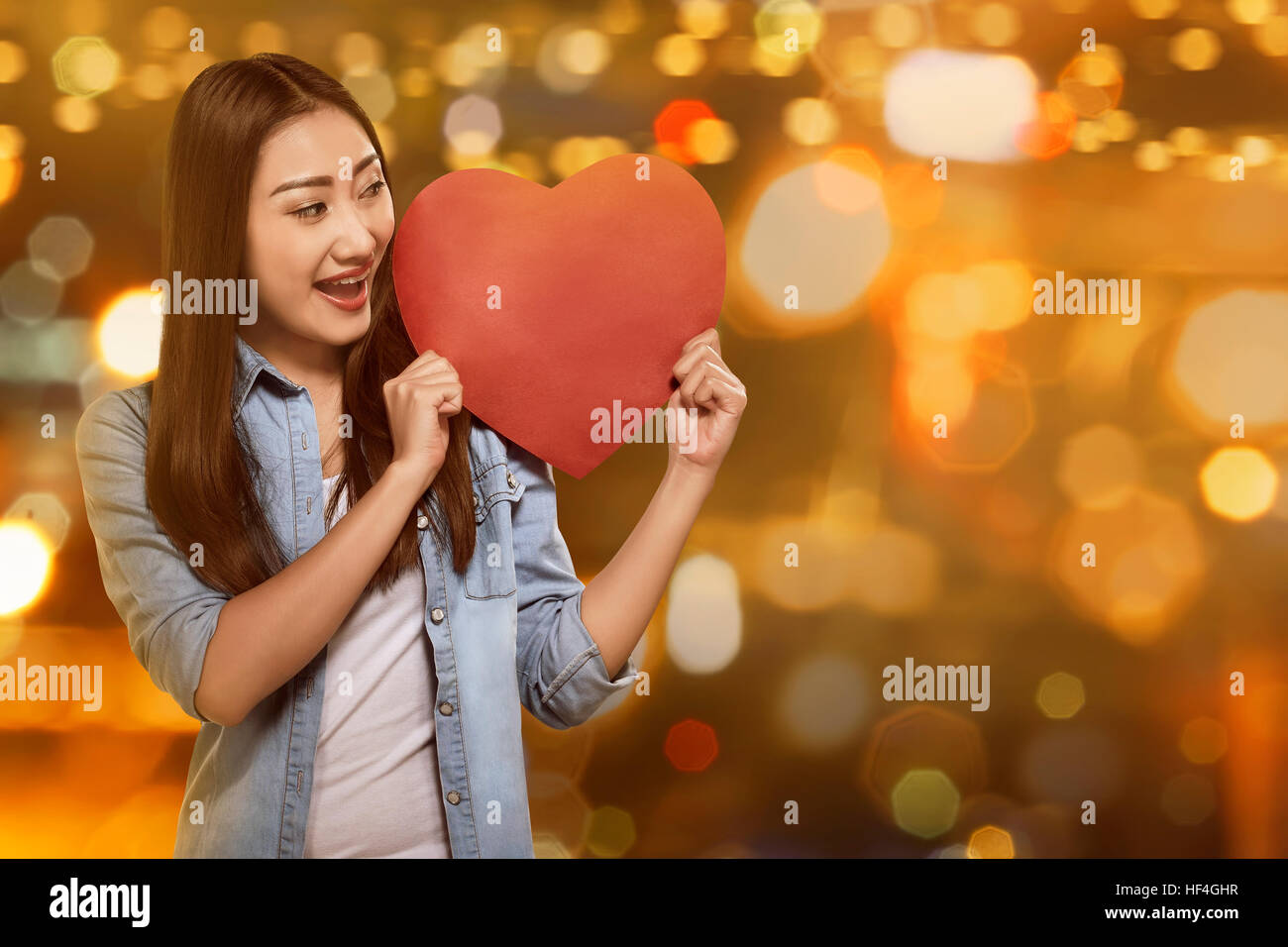 Attractive asian woman holding red heart against blurred light ...