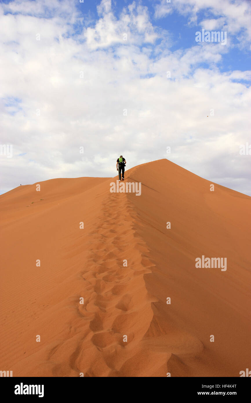 A tourist climbing a dune in the Sossusvlei desert, Namibia Stock Photo ...