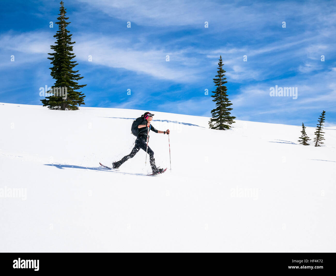 A young woman snowshoeing in the mountains of Mount (Mt) Rainier National Park Stock Photo