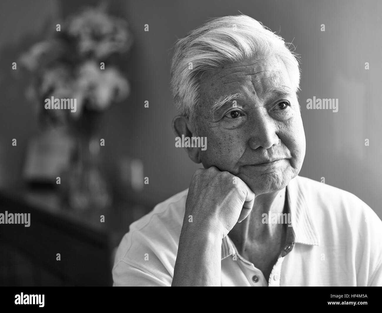 black and white portrait of a sad lonely asian senior hand on chin looking away thinking. Stock Photo