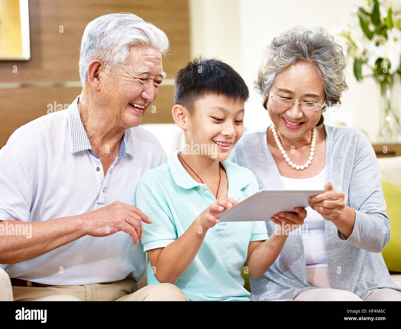 happy asian grandfather and grandmother looking at tablet computer with grandson, happy and smiling. Stock Photo