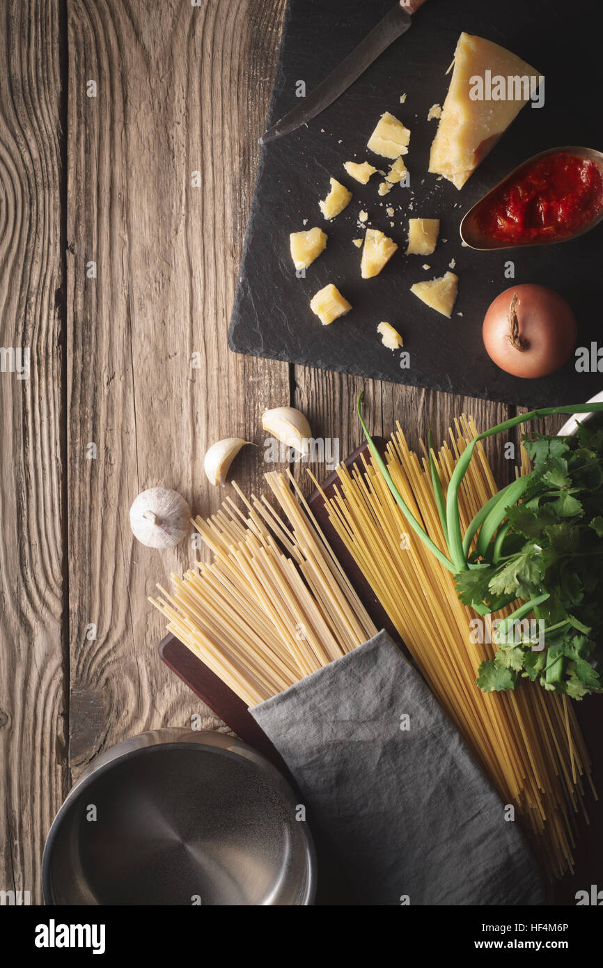 Ingredients for cooking spaghetti with cheese and fresh herbs on the old table vertical Stock Photo