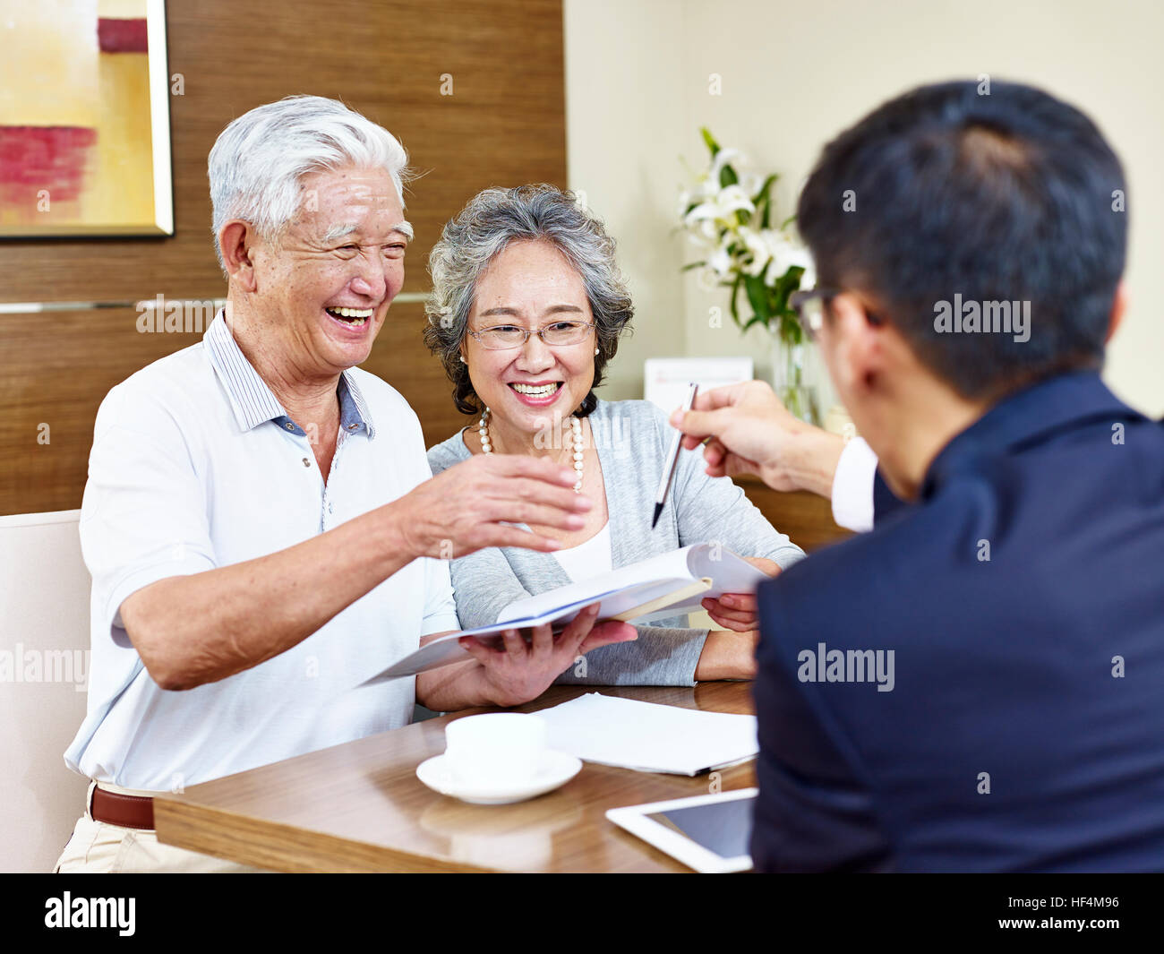 happy senior asian couple ready to sign contract taking a pen from a sales rep. Stock Photo