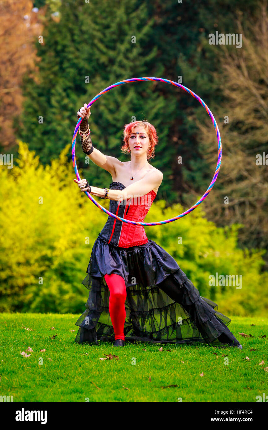 Young beautiful woman in circus costume play with hula hoop in the park  Stock Photo - Alamy