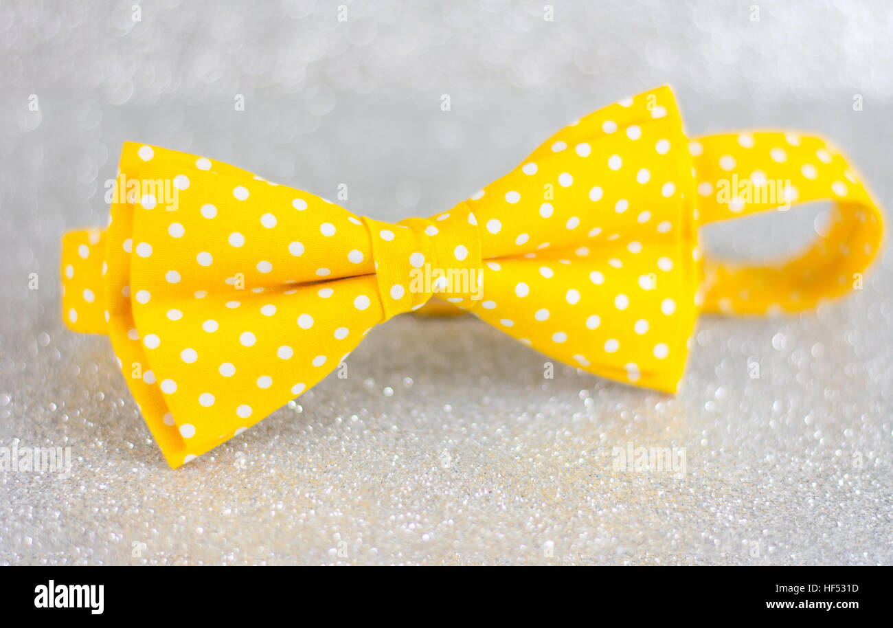 Yellow dotted bow tie on silver background Stock Photo