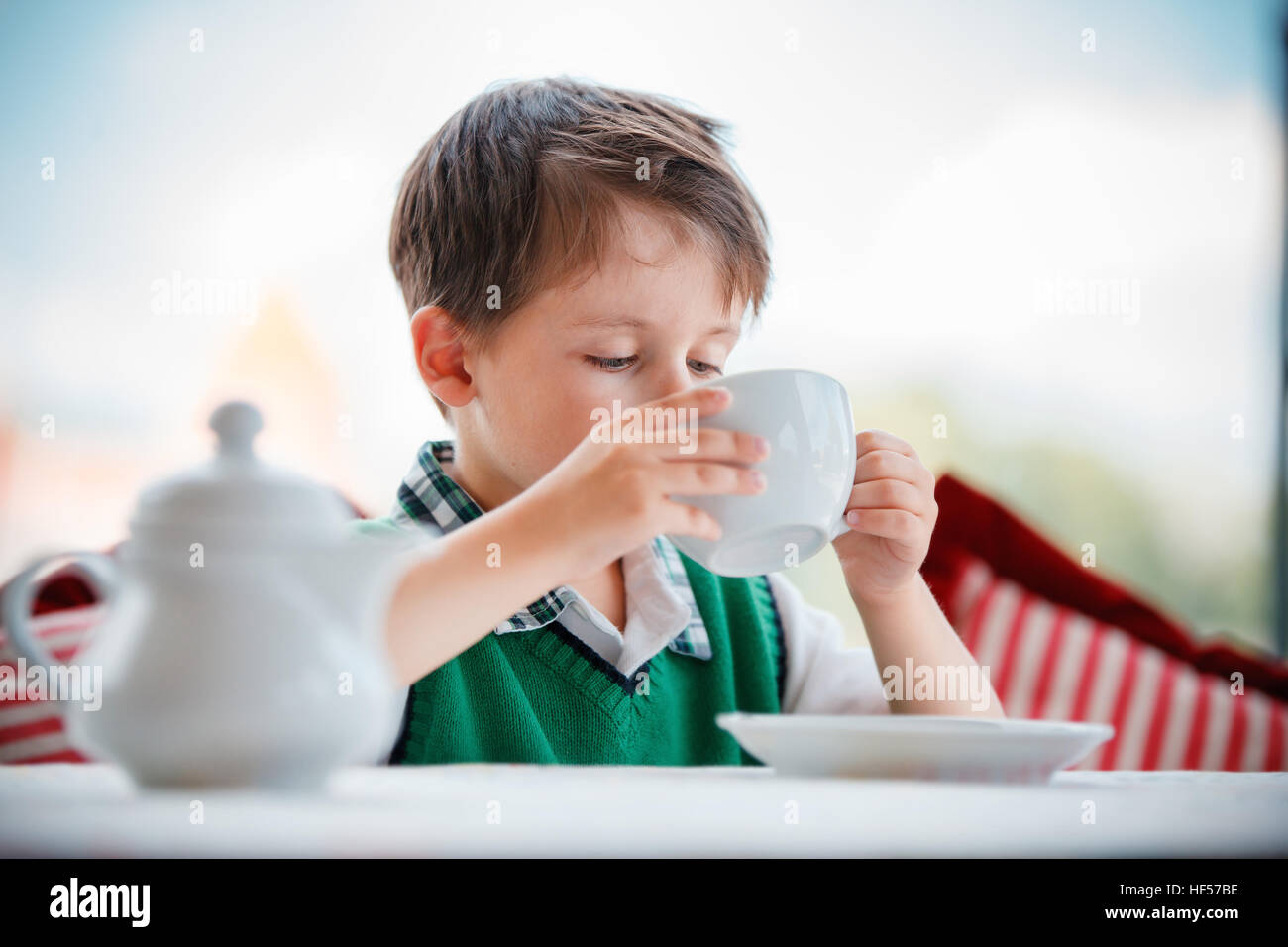 Cute little boy drinking tea in cafe Stock Photo Alamy