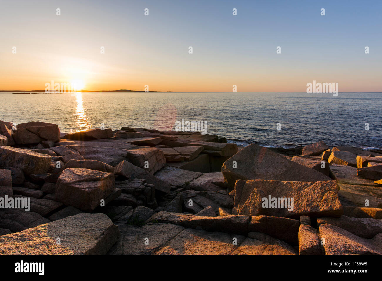 Golden sunrise illuminates the rocky coast at Acadia National Park ...