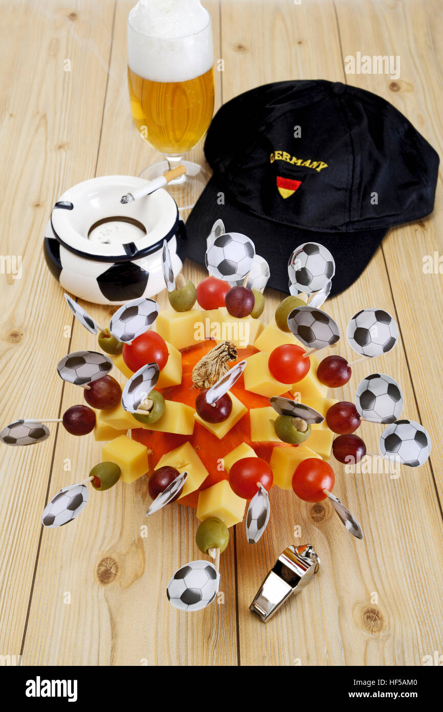Cheese snacks, finger food, football flags, football memorabilia, ashtray, football cap, whistle and a glass of beer Stock Photo