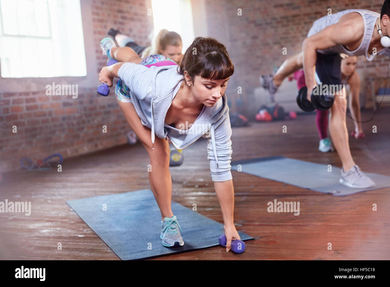 Exercise class balancing with dumbbells in gym studio Stock Photo
