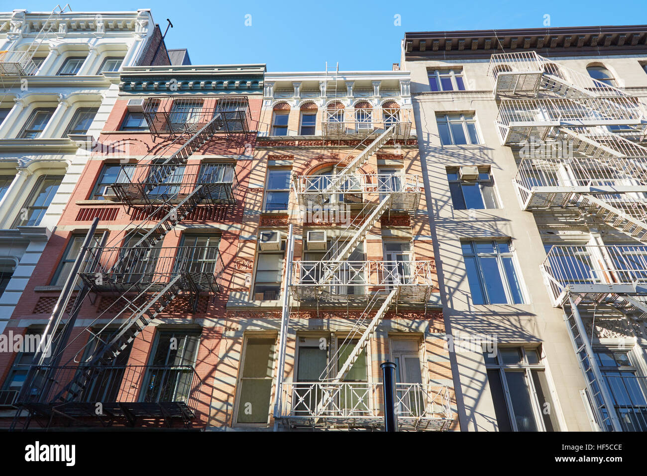 Houses facades with fire escape stairs, sunny day in Soho, New York Stock Photo