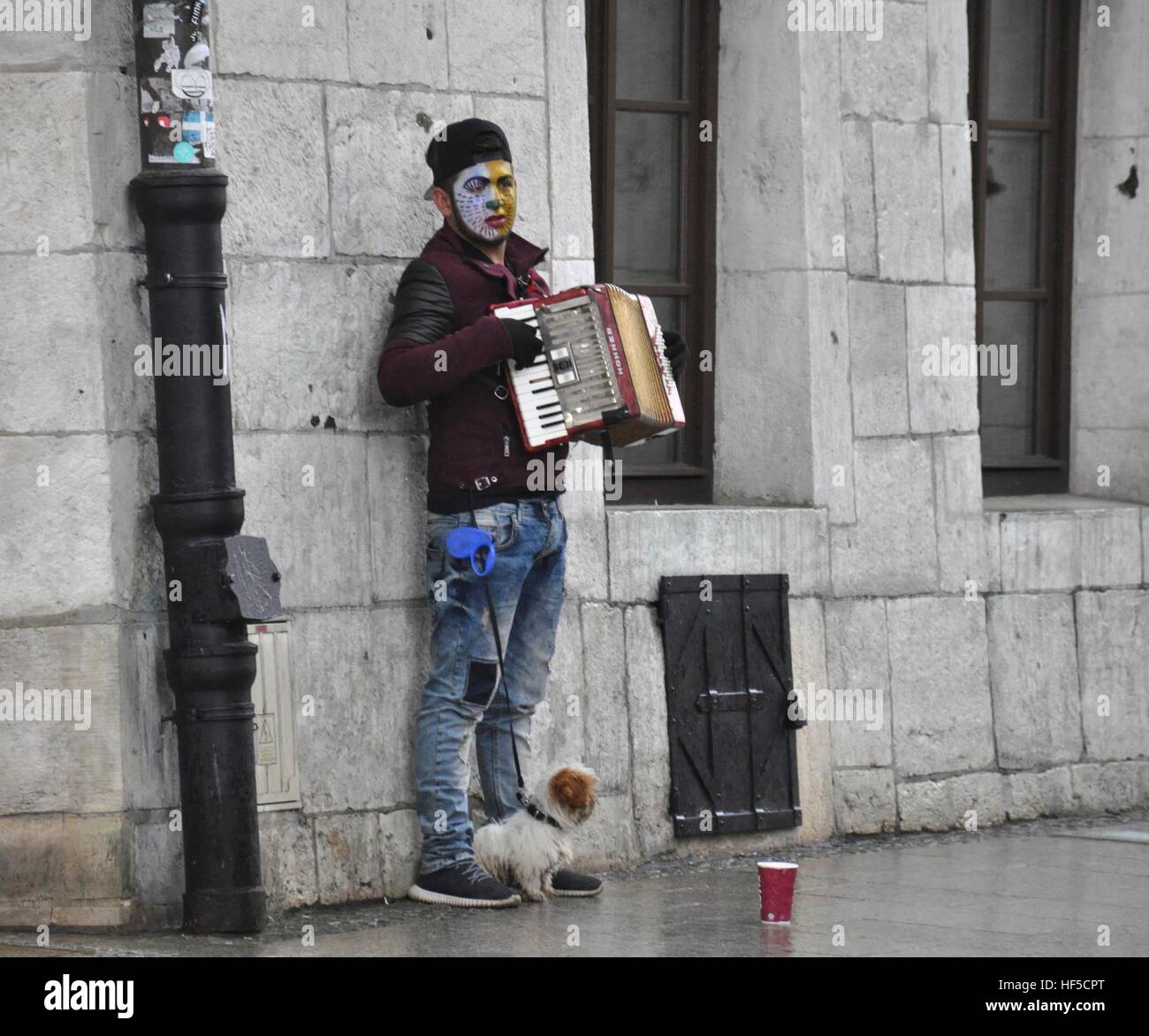 Young accordionist with his dog plays for money in Cracow, Poland Stock Photo