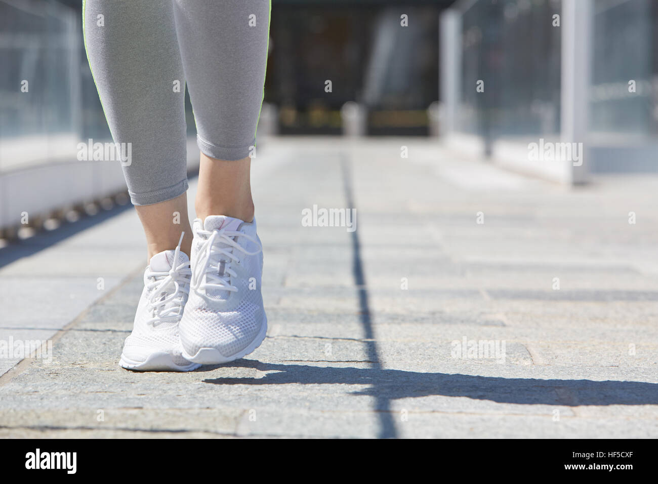 Woman running with white shoes outdoor in the city, sunlight Stock Photo