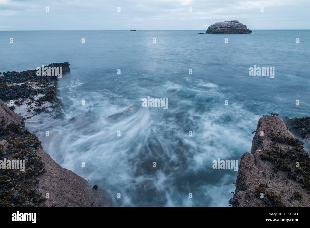 Waves wash against the rocky shoreline on the coast of Penninis Stock Photo