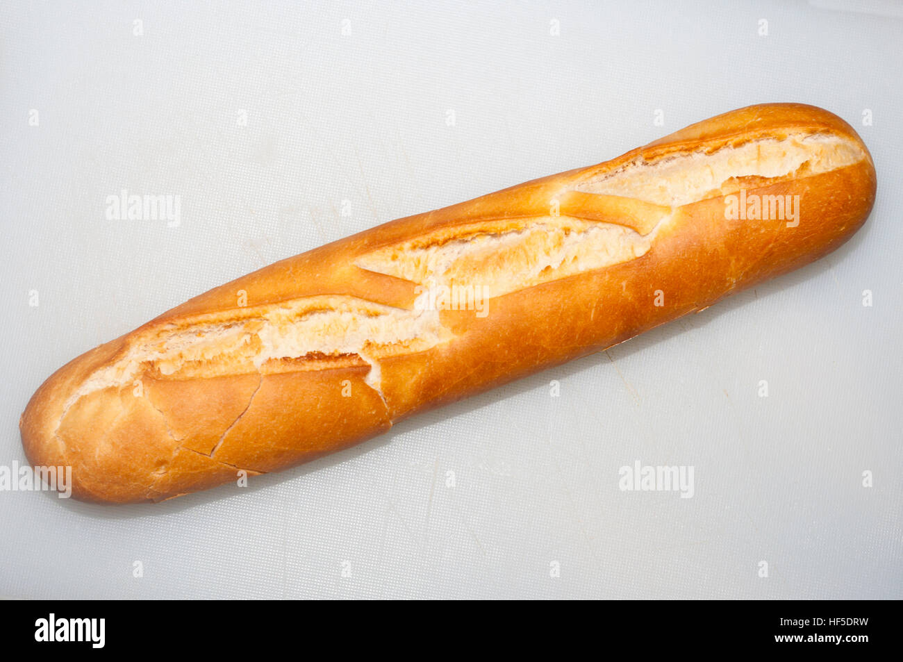 Baguette On A White Plastic Cutting Board Stock Photo