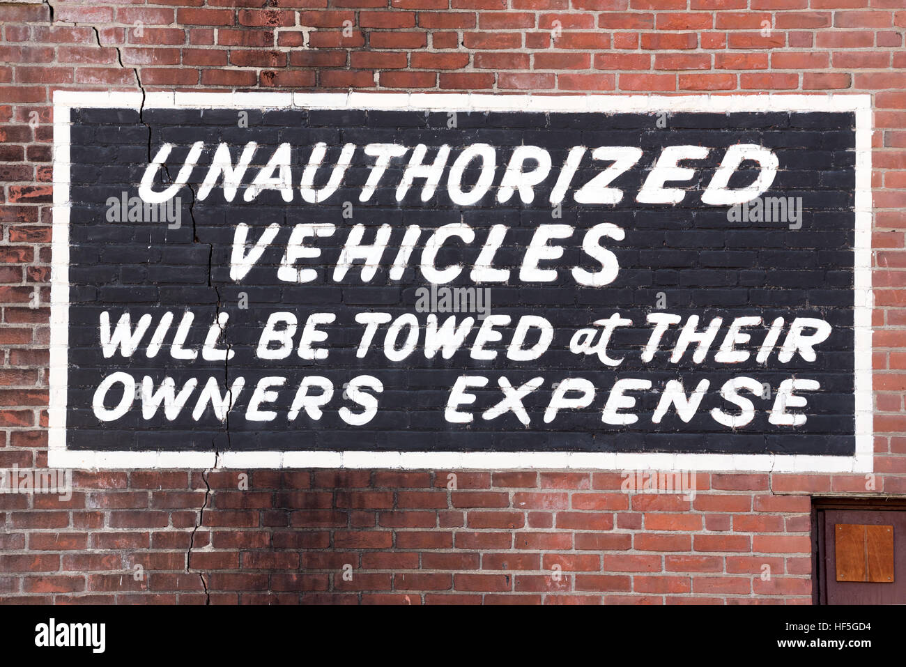Unauthorized vehicles sign painted onto a brick wall in Brattleboro, Vermont. Stock Photo