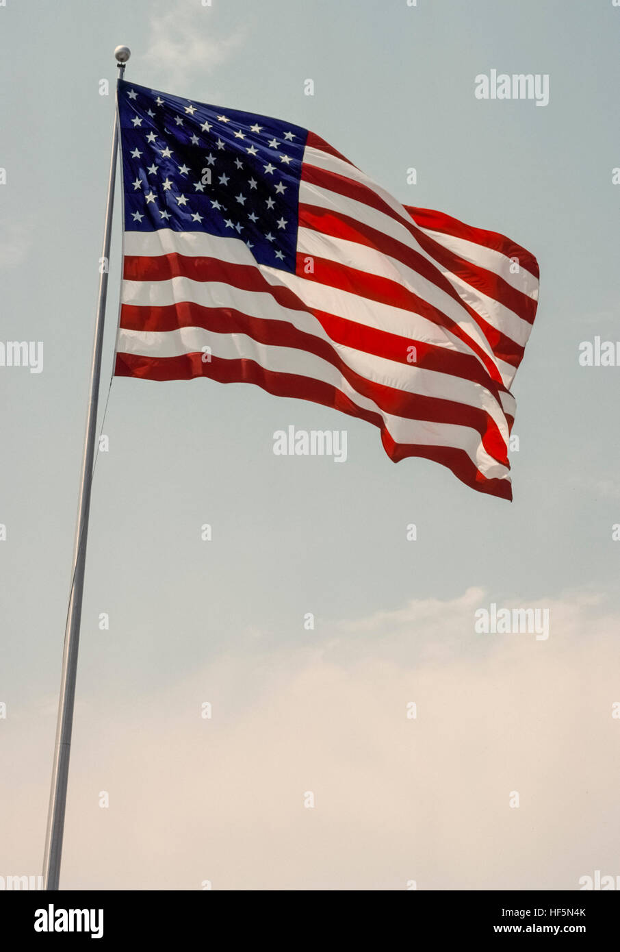 The national flag of the United States of America is known variously as the American flag, The Stars and Stripes, Old Glory, and The Star-Spangled Banner. The 50 five-pointed small white stars on a blue rectangular field represent the the 50 states of the U.S.A., while the 13 alternating red and white horizontal stripes represent the 13 British colonies in America that declared independence from Great Britain. Adopted in 1960, this is the 27th version of the U.S. flag that was first designed in 1777. Stock Photo