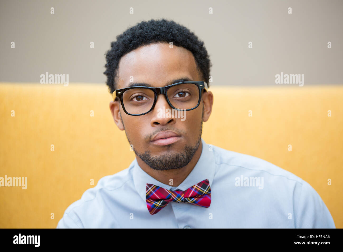 Closeup portrait headshot, high iq, intelligent guy with black glasses and bow tie, isolated yellow white background Stock Photo